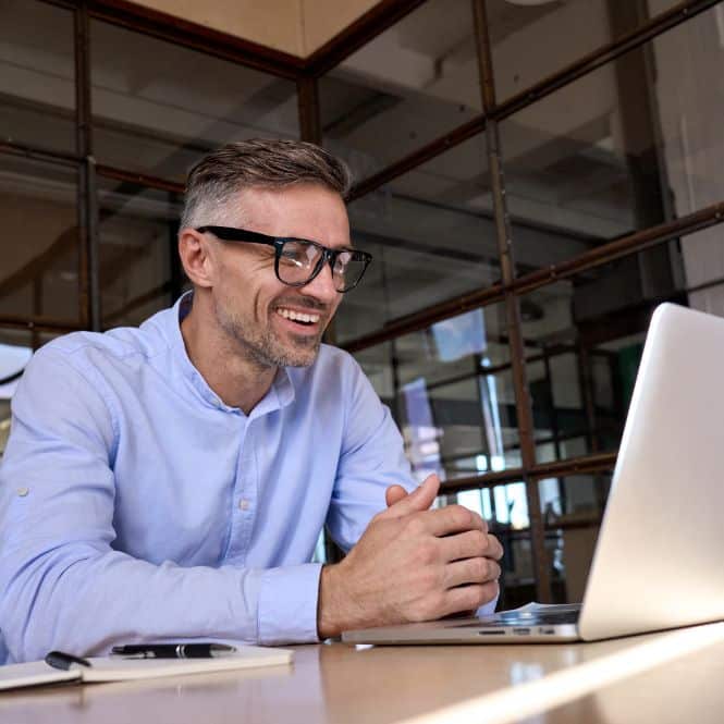 man smiling at laptop, symbolic of law firm coaching online.